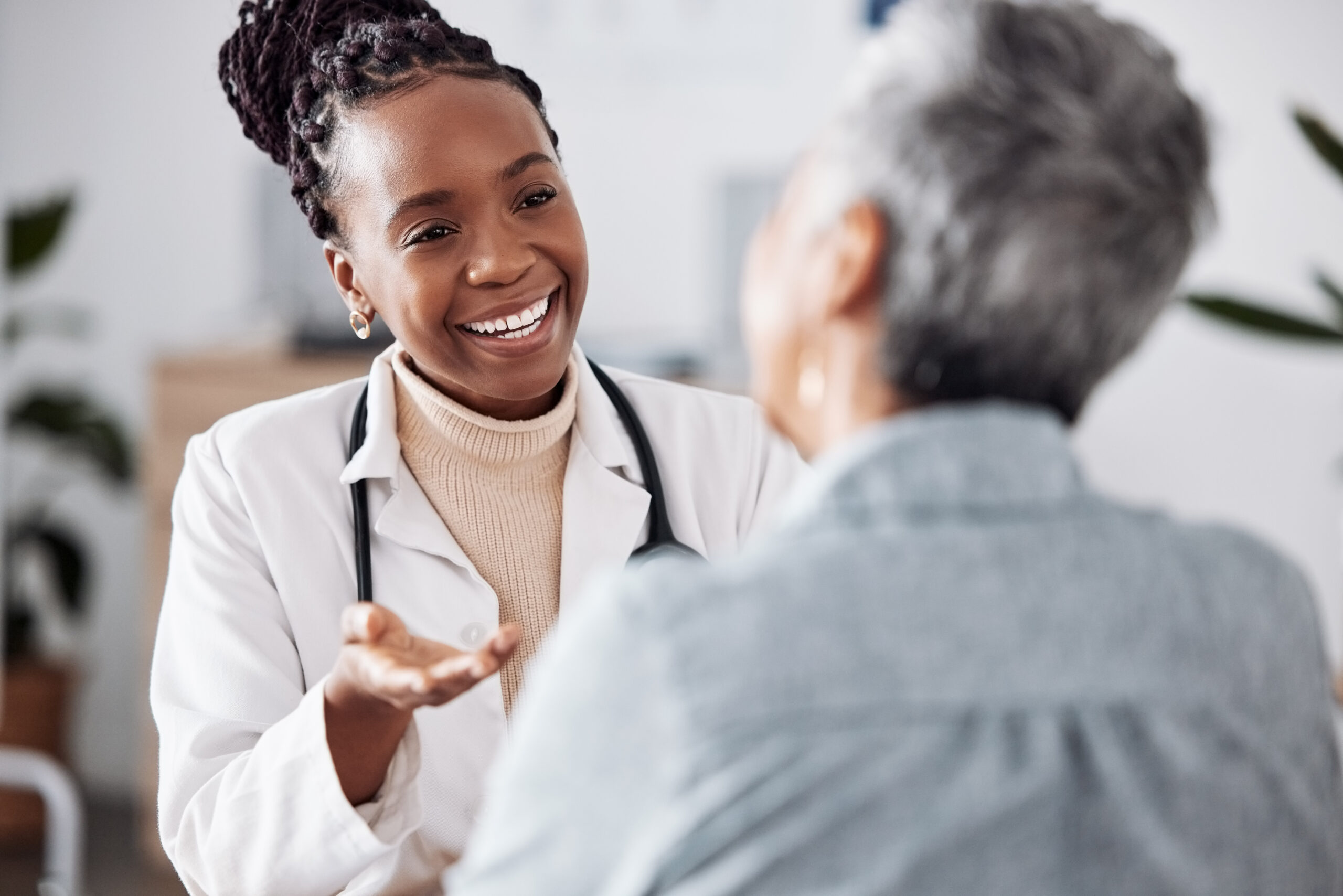 Smile, black woman or doctor consulting a patient in meeting in hospital for healthcare feedback or support. Happy, medical or nurse with a mature person talking or speaking of test results or advice.